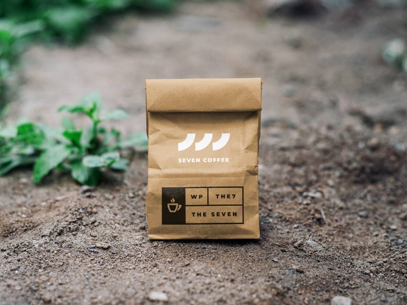 A brown bag sitting on the ground with some plants in it