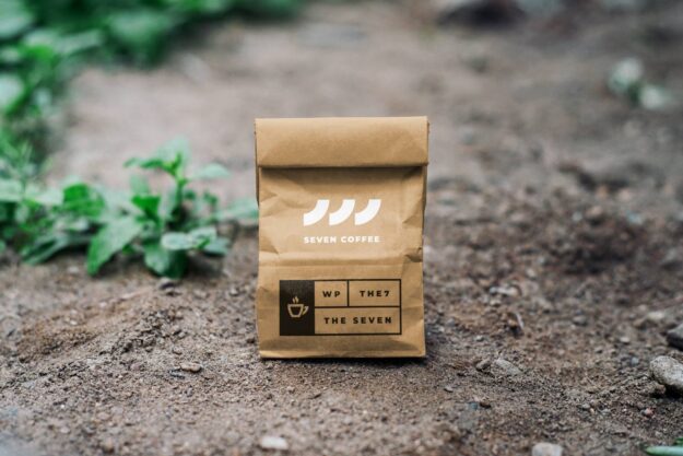 A brown bag sitting on the ground with some plants in it