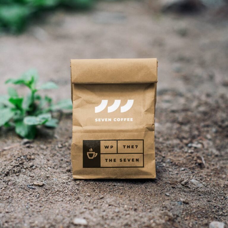 A brown bag sitting on the ground with some plants in it