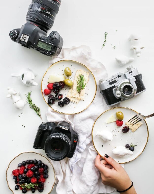 A table with plates of food and cameras on it