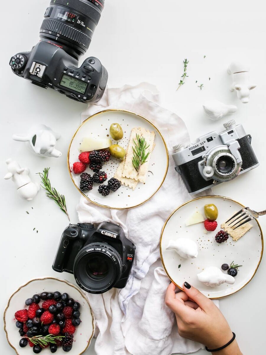 A table with plates of food and cameras on it