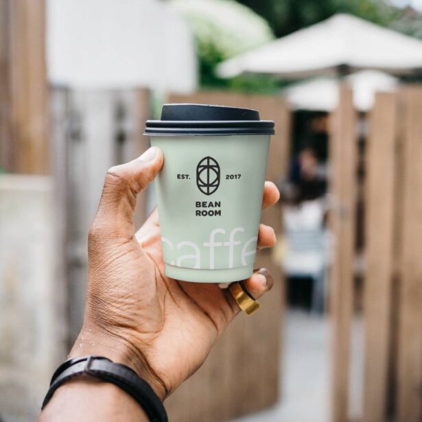 A person holding up a coffee cup in their hand.