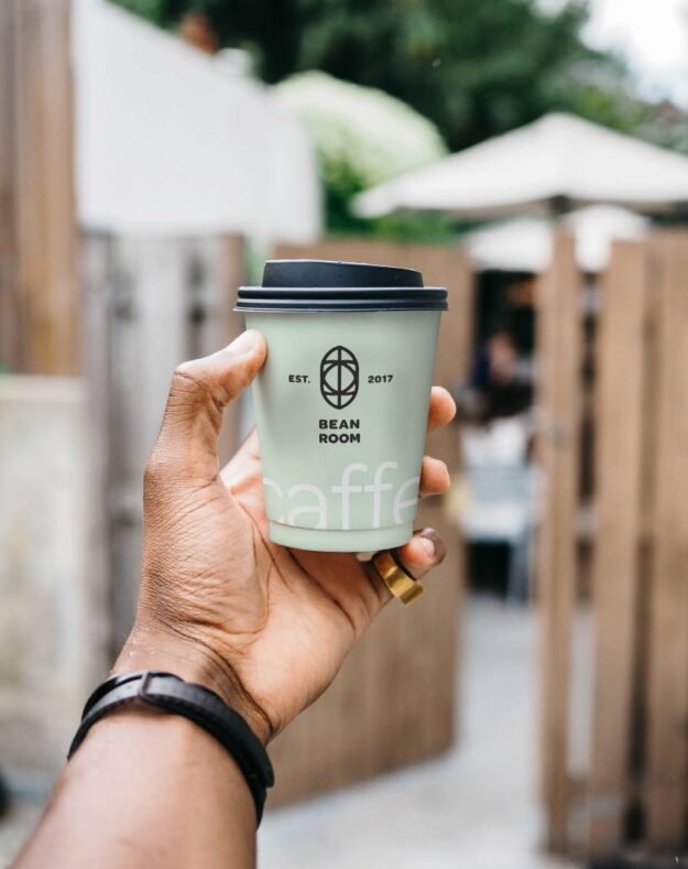 A person holding up a coffee cup in their hand.