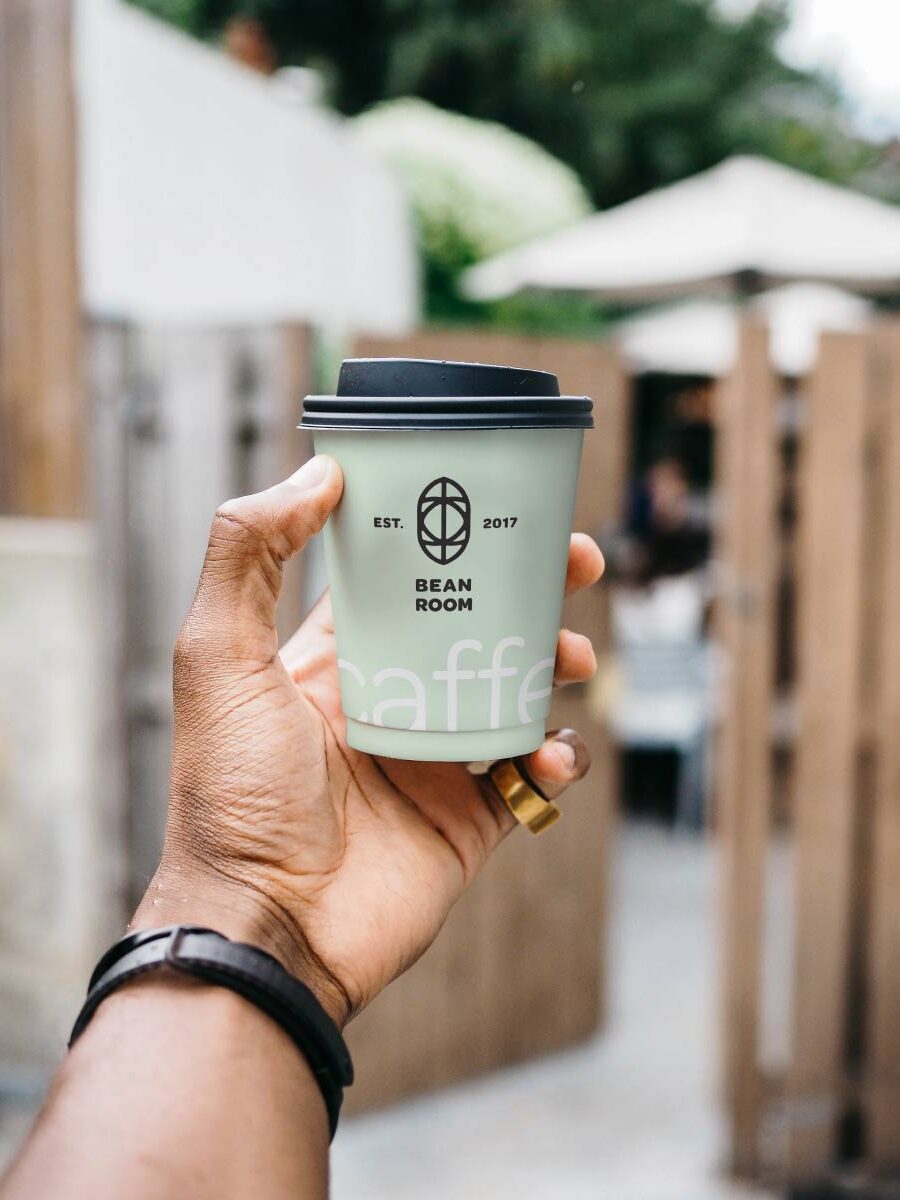 A person holding up a coffee cup in their hand.