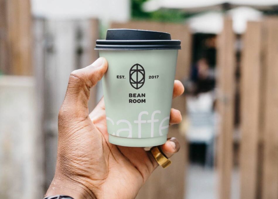 A person holding up a coffee cup in their hand.
