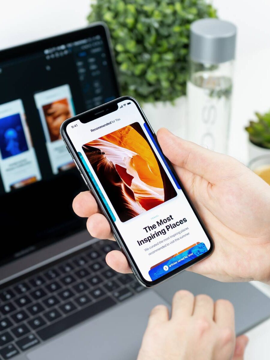 A person holding an iphone in front of a laptop.