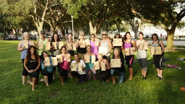 A group of people holding up boxes in the grass.