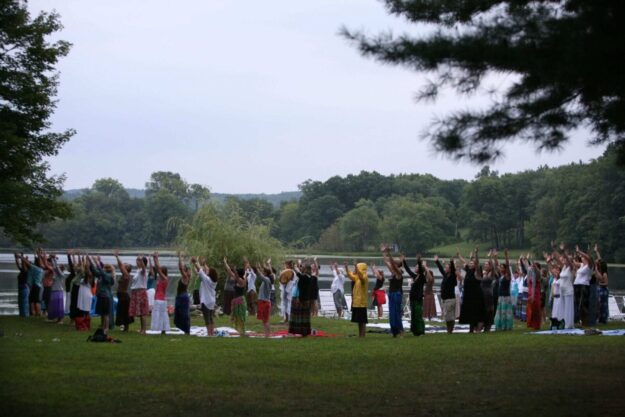 A group of people standing in the grass with their hands raised.