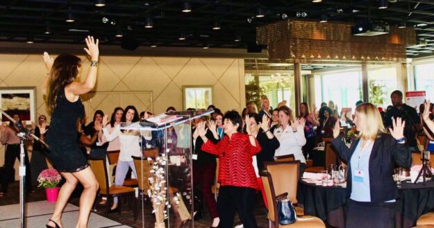 A group of people in a room with one woman standing up.