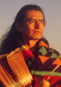 A man in native american clothing with long hair.