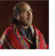 A man with long hair and wearing a colorful blanket.