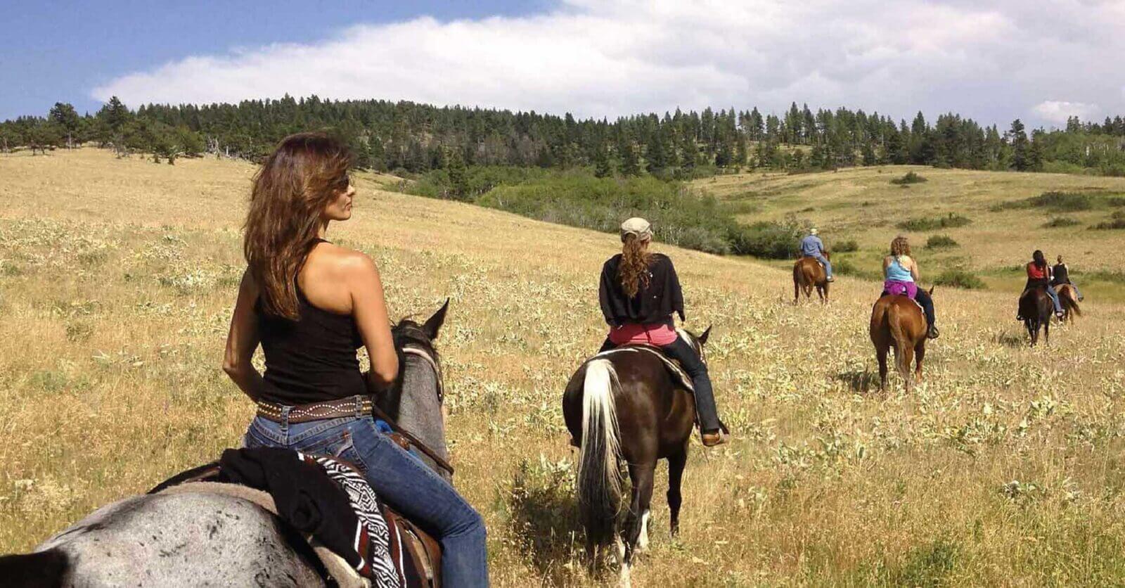 A group of people riding horses through the grass.