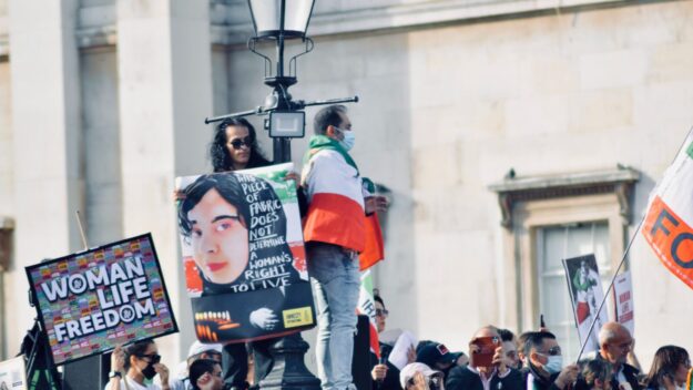 A person holding up a poster in front of a crowd.