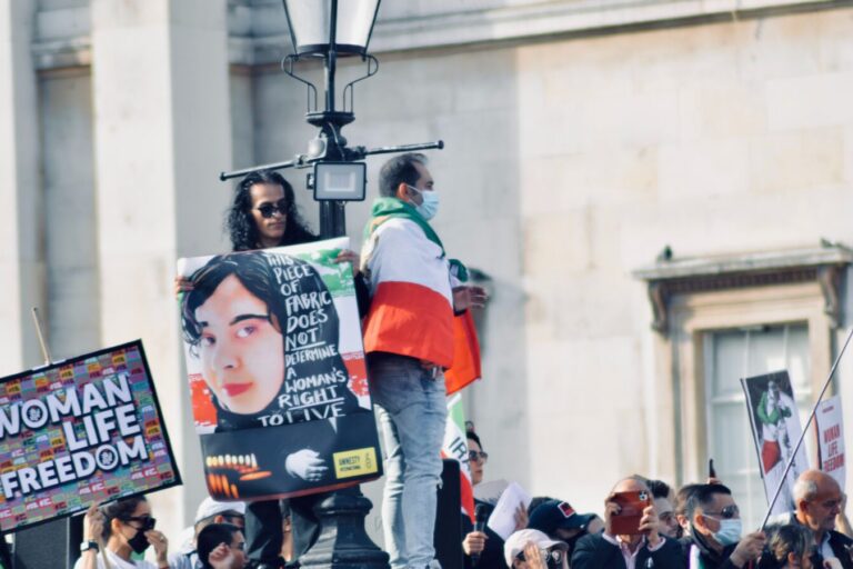 A person holding up a poster in front of a crowd.