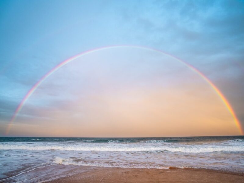 A rainbow over the ocean and beach.