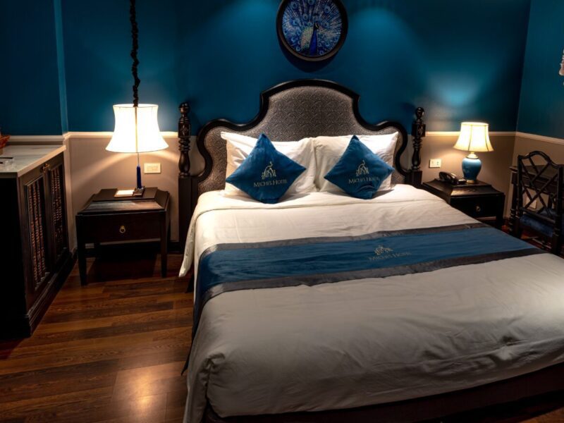 A bedroom with blue walls and white bedding.