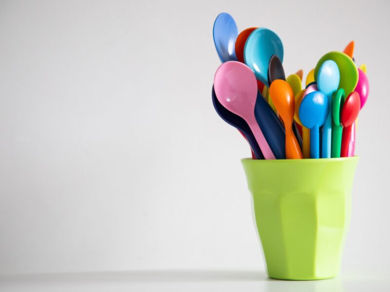 A cup full of spoons and forks on top of a table.