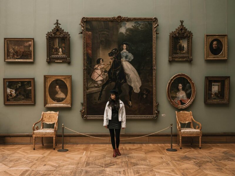 A woman standing in front of several paintings.
