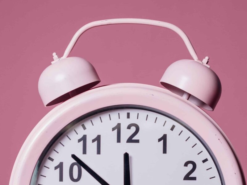 A pink alarm clock on top of a table.