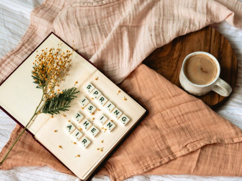 A book with a flower on top of it next to a cup.