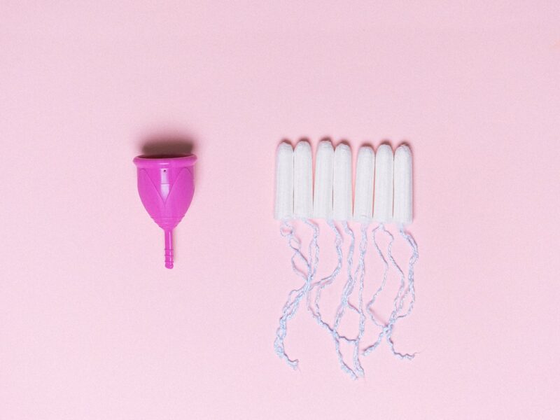 A pink menstrual cup and six white tampons.