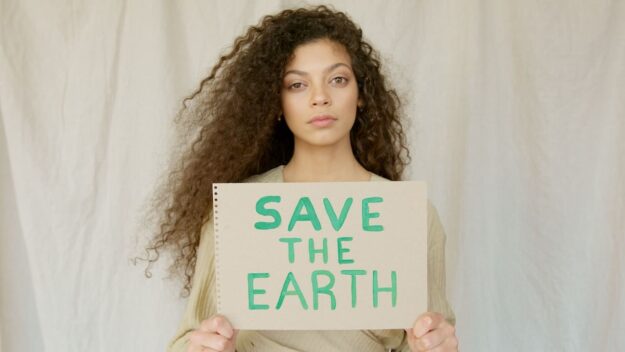 A woman holding up a sign that says save the earth.