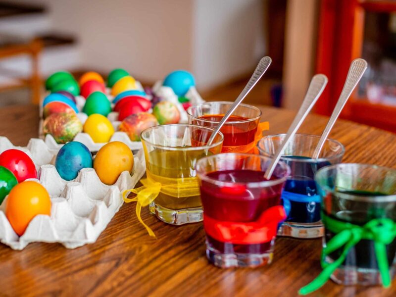 A table with cups of colored liquid and eggs.
