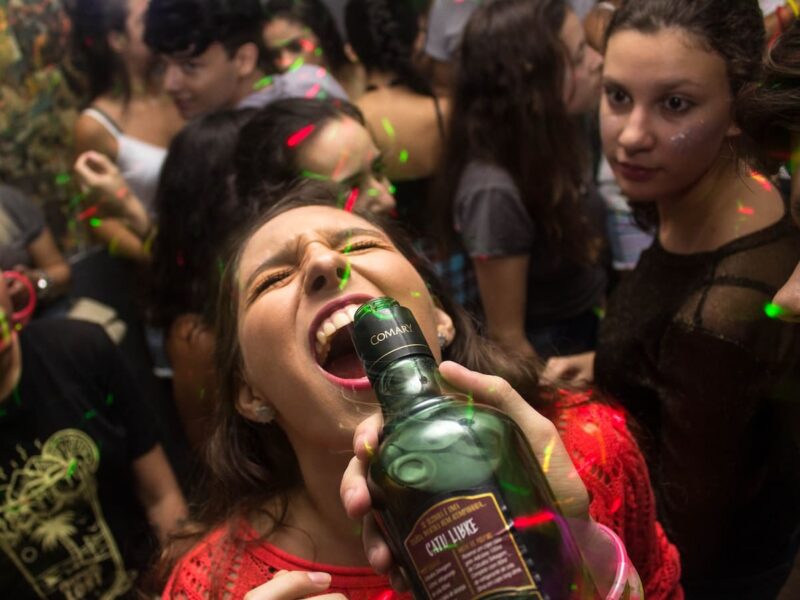 A woman is drinking from a bottle of alcohol.