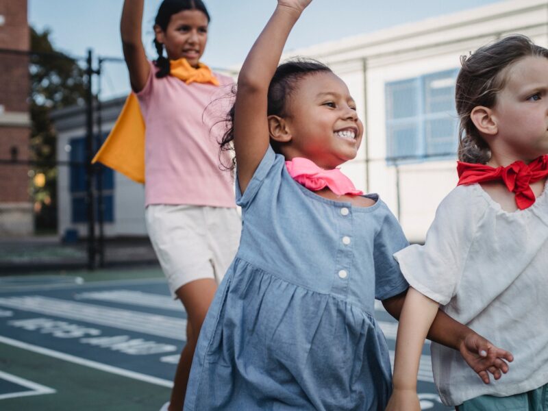 A group of children standing on top of a road.