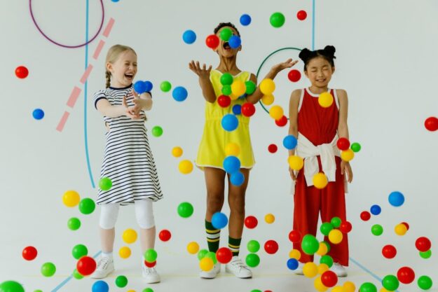 Three children are playing with balls in a room.