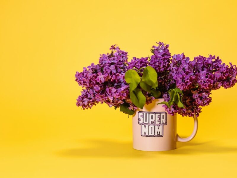 A mug with purple flowers in it on a yellow background