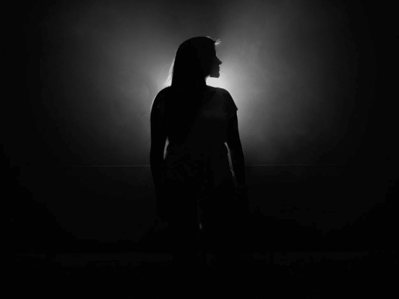 silhouetted-woman-standing-against-bright-light